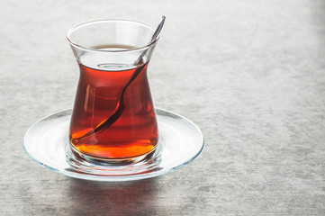 Glass Turkish brewed black tea on black rustic background. Turkish traditional hot drink 