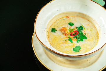 Vietnamese Tom Yum soup with seafood. Yellow soup with shrimp, scallop, mussels, salmon in a dark...