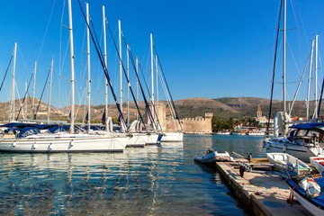 Obraz premium Summer morning in the harbor. Yachts parking in harbor, Harbor in Trogir, Croatia. Sailboats reflected in water. Boat rental.