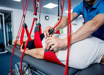 Physiotherapy. Suspension training therapy. Young man doing fitness traction therapy with...