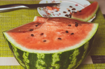 half a watermelon and a knife in the background, toned image