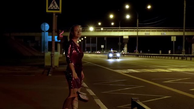 prostitute on side of road waiting for client at night. adult woman is engaged in prostitution.