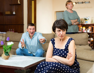 Unhappy woman during family conflict, emotional man on background