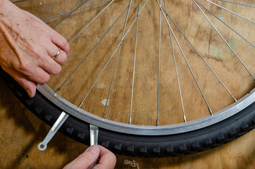 overhead view of a bicycle wheel and tire with a man's hands using tire removal tools