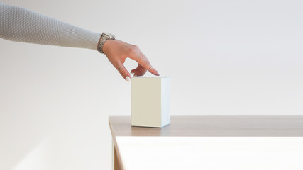 A elegant woman hand holds light blue box on a wooden table. Perfume present for her. Mock up. 