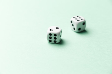 White gaming dice on mint background. Top view. Flat lay. Copy space. Game of chance concept. Close-up. Pastel colors