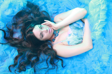 Young Woman Portrait in Evening Blue Long Dress on studio background