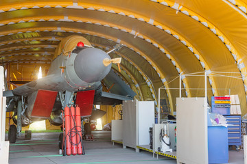 Wing military fighter with folded wings in the garage of the hangar on service repair.