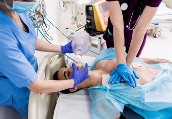 Doctors give resuscitation to a male patient in the emergency room. Cardiac massage