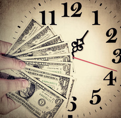 Hands holding money. American dollars banknotes in man hands against the clock. Old paper textured image