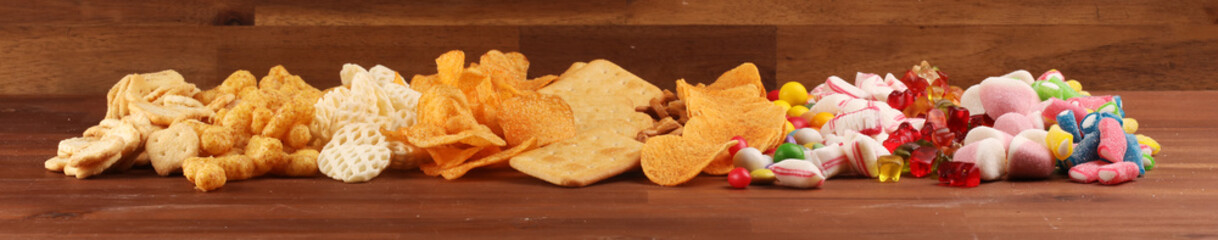 Salty snacks. Pretzels, chips, crackers and candy sweets on table
