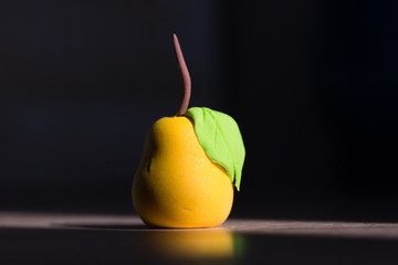 clay miniature yellow pear on a dark blurred background