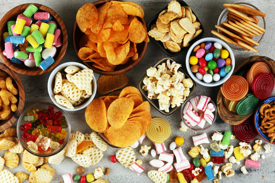 Salty snacks. Pretzels, chips, crackers and candy sweets on table