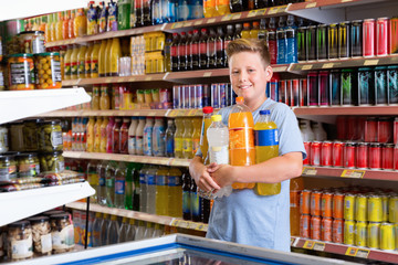 Portrait of happy preteen boy with purchases in supermarket
