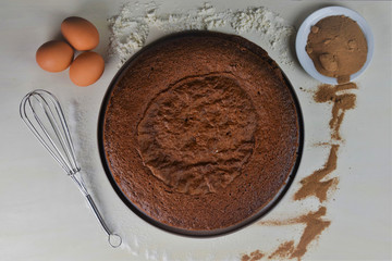 Pastel casero de chocolate, con algunos de sus ingredientes sobre la mesa