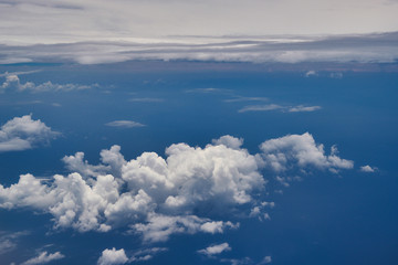 Fototapeta na wymiar Flying over whitre puffy clouds and ocean headed towards the Cayman Isalnds