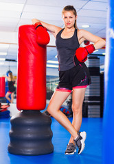 Potrait of woman boxer who is standing near punching bag