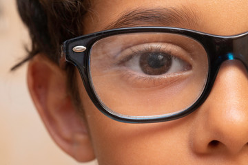 An extreme closeup view on the eye of a 10 year old boy wearing glasses, sweet and innocent kid...