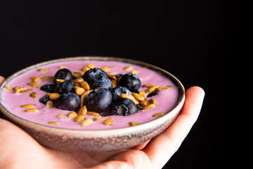 Tasty fresh blueberry yoghurt shake dessert in ceramic bowl standing on black dark table background.