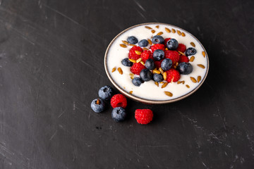 Tasty fresh blueberry raspberries  yoghurt shake dessert in ceramic bowl standing on black dark table background.