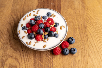 Tasty fresh blueberry raspberries  yoghurt shake dessert in ceramic bowl standing on black dark table background.
