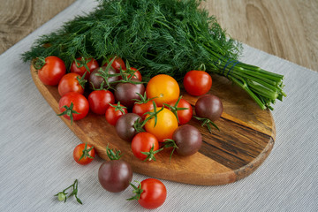 Red tomato on a cutting board with dill on textile background. Copy space. Fresh tomato based for cooking.