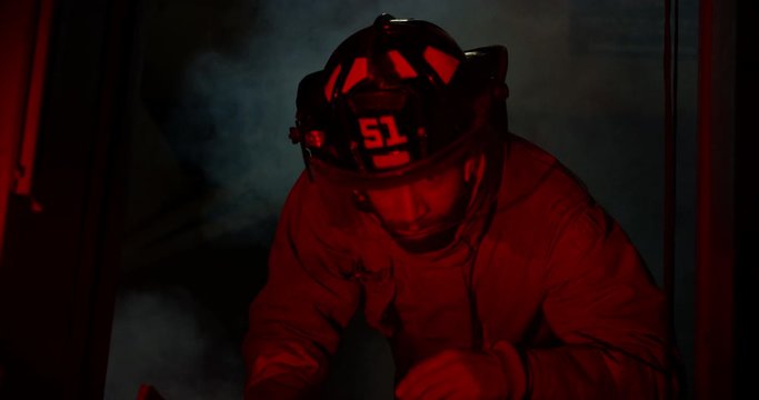 Fire Fighter climbing up lader with smoke billowing below - close up on face