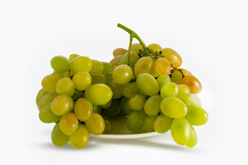 Brush green grapes lying on a plate, close-up. Isolated on white background.