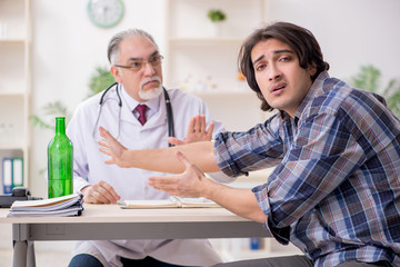 Obraz premium Young male alcoholic visiting old doctor