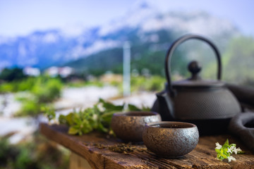 Two cups of green tea and teapot on wooden table and nature background with copy space