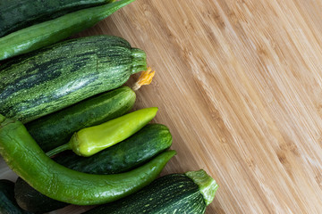 Green vegetables lie in a row on a brown wooden background on the left, on the right is an empty place, top view