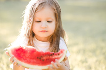 Cute kid girl 3-4 year old eating ripe watermelon outdoors closeup. Childhood. Summer time.