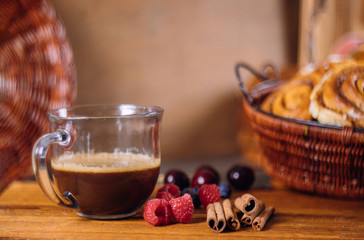 Cup of coffee with cinnamon rolls on the wooden table.