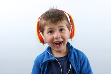 Ein fröhlicher Junge mit einem fehlenden Milchzahn lächelt beim Musikhören