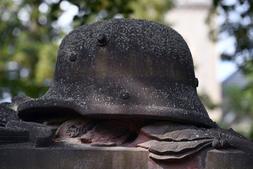 A weathered sandstone sculpture of a world war 2 helmet on the tomb of a German soldier. 