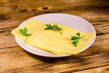 Sliced cheese and parsley in ceramic plate on wooden table