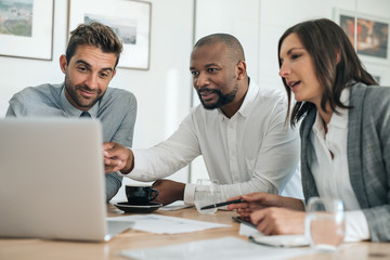 Smiling businesspeople working with a laptop during an office meeting