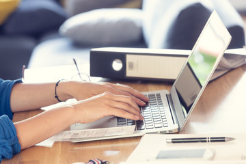 Home office. Woman's hands are typing on laptop keyboard. Shallow depth of field.