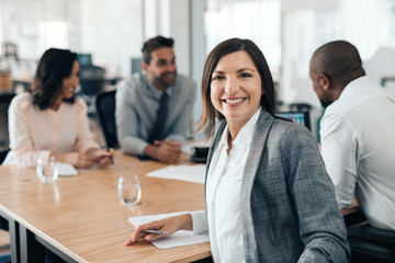 Smiling businesswoman sitting with colleagues during an office meeting