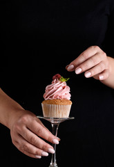 The process of making cupcakes, coating a cream from a pastry bag in the hands of a pastry chef.