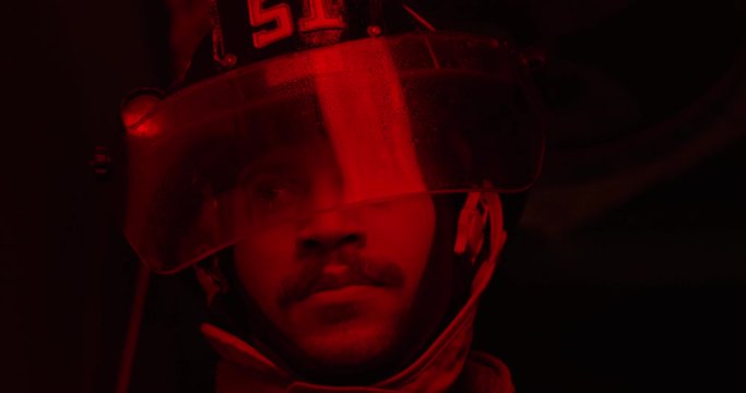 Fire Fighter under red light with water on visor - close up on face