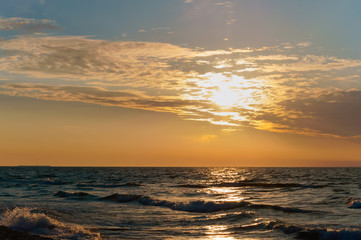 Sunset over the sea. Reflection of sunlight in the sea waves. The sky in the sunset rays.