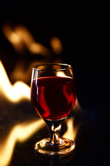 red drink with fire behind and reflection on black background