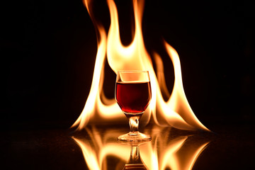 red drink with fire behind and reflection on black background