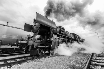 Black and white photo of an old steam locomotive with steam all around