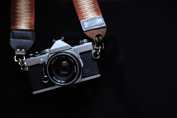 retro camera with a strap on a black background. low key photo and copy space