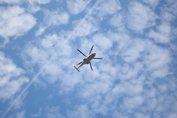 A helicopter flies in the sky. Propeller transport on a background of blue sky. Bottom view of the movement of the aircraft.
