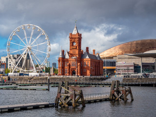 Cardiff Bay,  Cardiff, Wales. Late afternoon in Cardiff Bay with a dark sky over the old Pierhead building and the sun glinting on the Millennium Centre roof.  The old staithes still prominent.