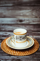 Tasse de café en porcelaine blanche et dorée sur une table en bois vintage