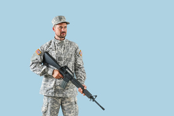 Soldier with assault rifle on color background